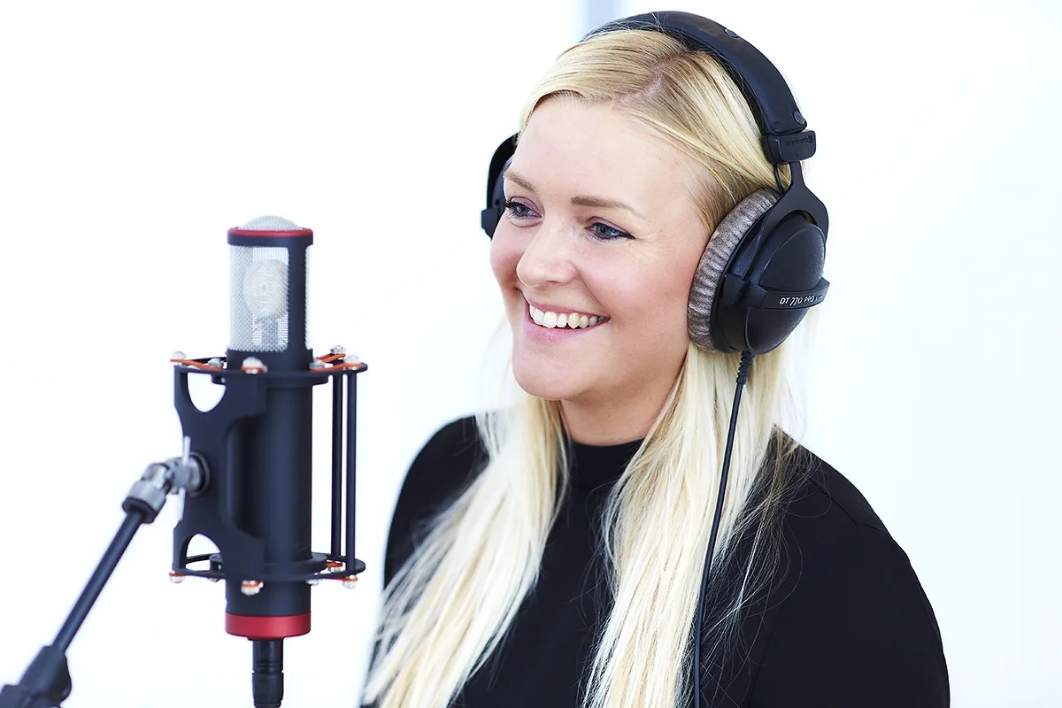 Sanger griner ved mikrofonen i Lydstudiet