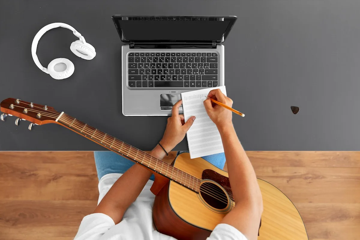 Sangskriver arbejder på en bryllupssang med guitar og noter