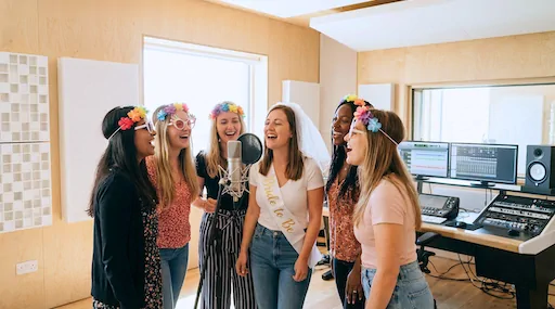 Gruppe til polterabend med blomsterkranse synger sammen om mikrofonen i Lydstudiet